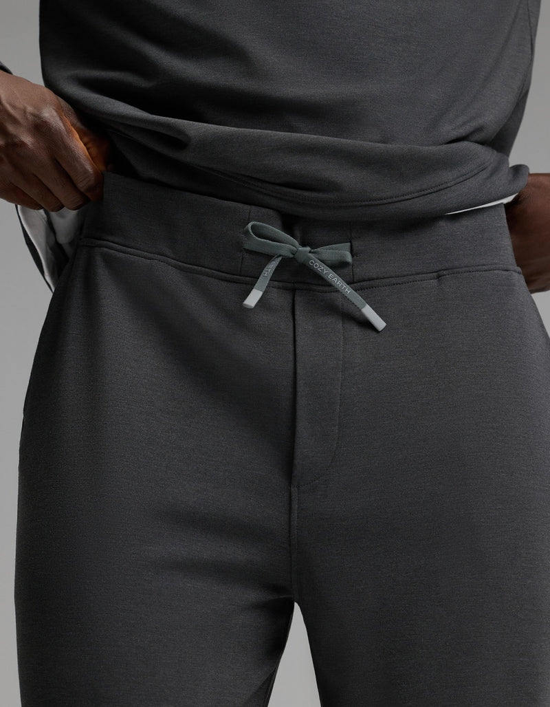 A person wearing Cozy Earth Men’s Brushed Bamboo Joggers in dark gray with a drawstring, paired with a matching shirt, hands resting on their hips.