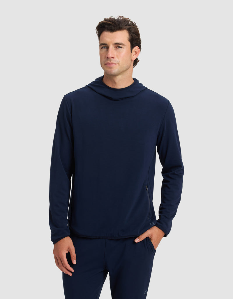 A man stands facing forward with one hand in his pocket, wearing the Cozy Earth Men's Brushed Bamboo Recovery Hoodie and matching pants against a plain light gray background.