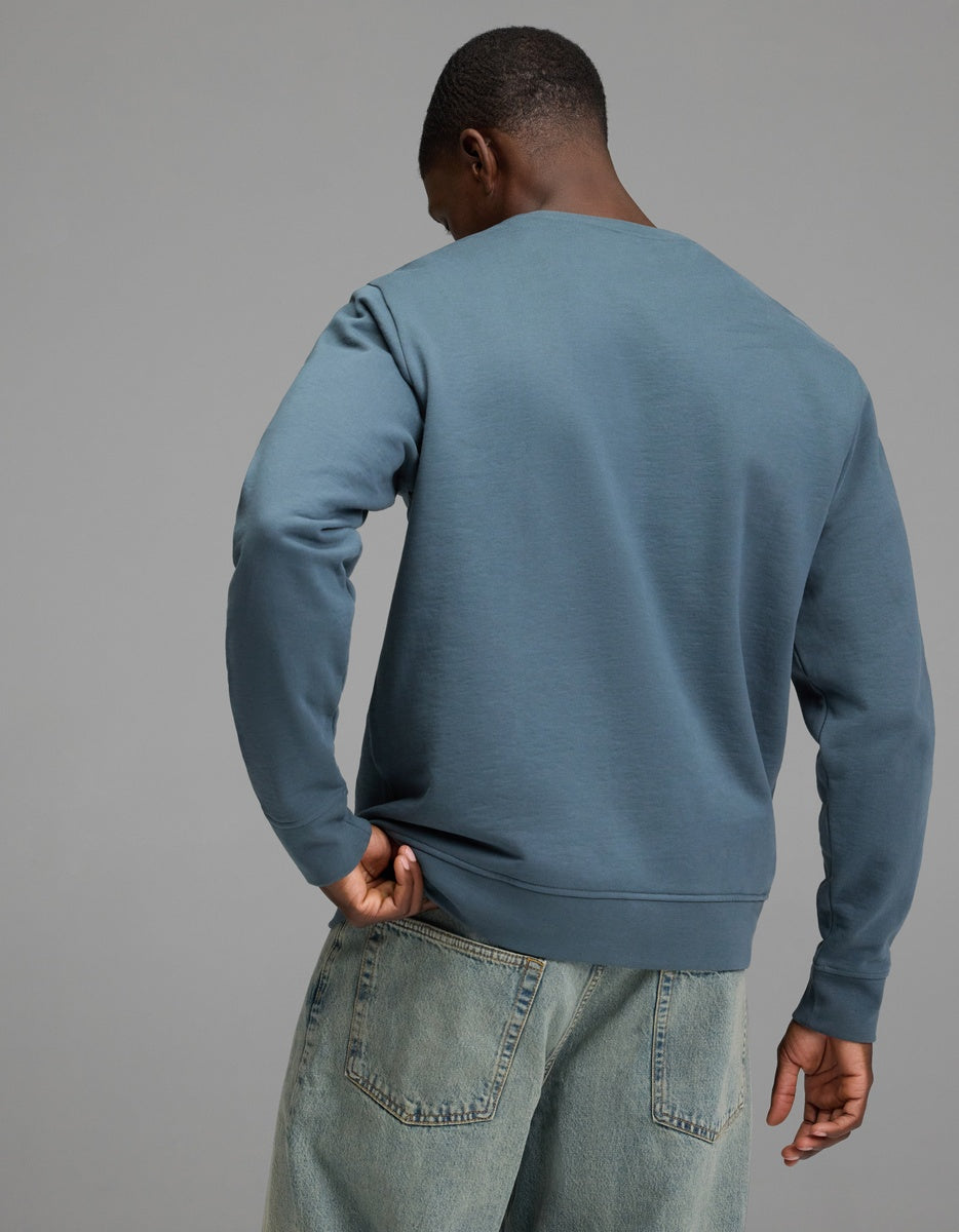 A person wearing the Cozy Earth Men’s Dylan Crewneck and light blue jeans stands with their back to the camera against a plain gray background.|Color:Dawn