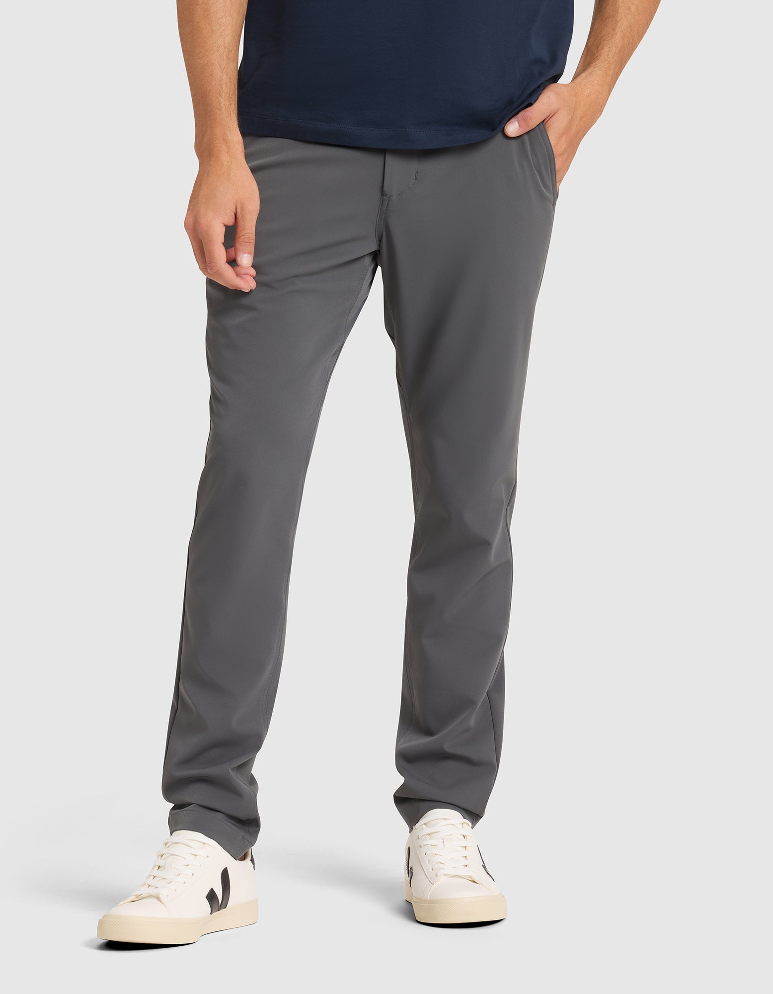 A person wears Cozy Earth Men's Everywhere Pant with white sneakers featuring black details, against a plain light background. Only the lower half is visible, with one hand in a pocket. |Color:Coal