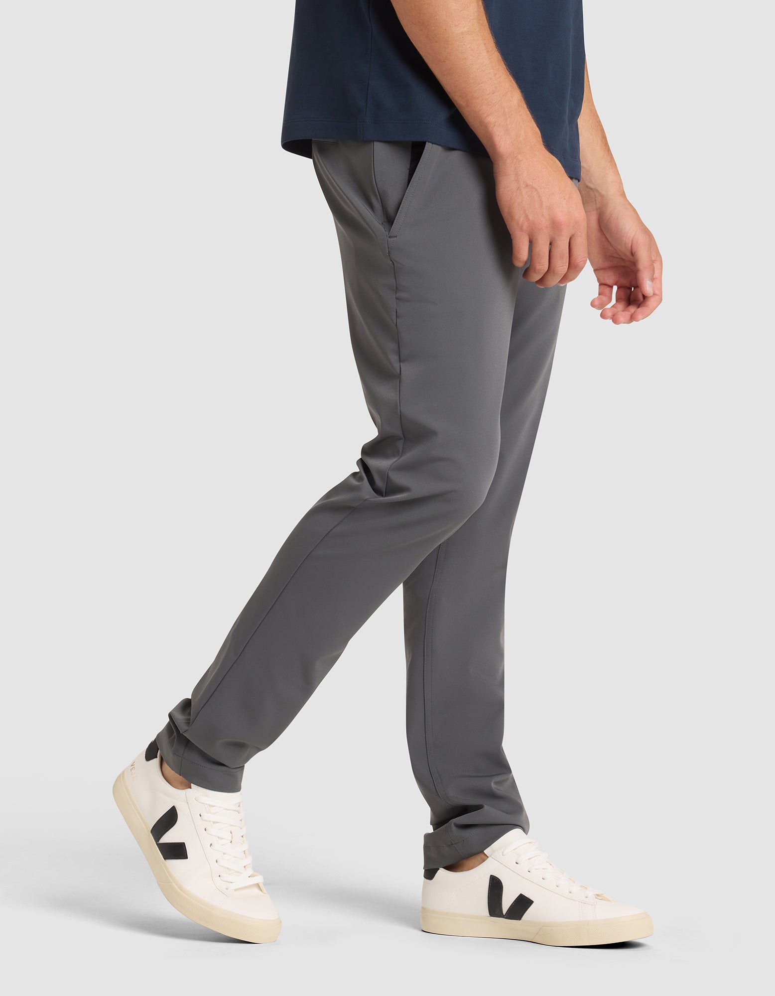 A man models the Cozy Earth Men's Everywhere Pant in gray with a navy shirt and white sneakers featuring black "V" logos, standing against a plain gray background, shown from shoulder to feet.  |Color:Coal