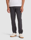 A person wearing Cozy Earth's Men's Everywhere Pant in dark gray stands against a plain light background, paired with a white t-shirt and white sneakers with tan soles. The image is cropped from the shoulders down.  |Color:Graphite