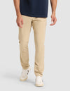 A model wears Cozy Earth's Men's Everywhere Pant in beige, paired with a navy shirt and white sneakers with black accents, standing against a plain light gray background. The image is cropped from the shoulders down. |Color:Khaki