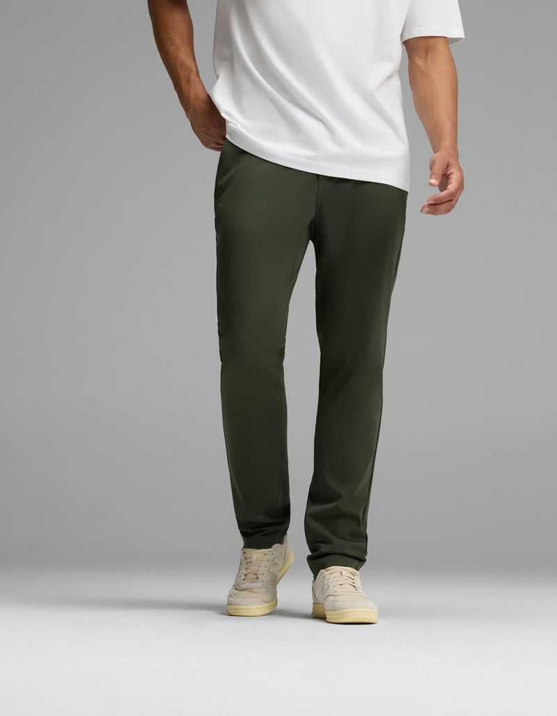 A person wearing Cozy Earth’s Men’s Everywhere Pant in olive green is pictured standing against a plain gray background. The image is cropped at the shoulders, focusing on the lower torso and legs.