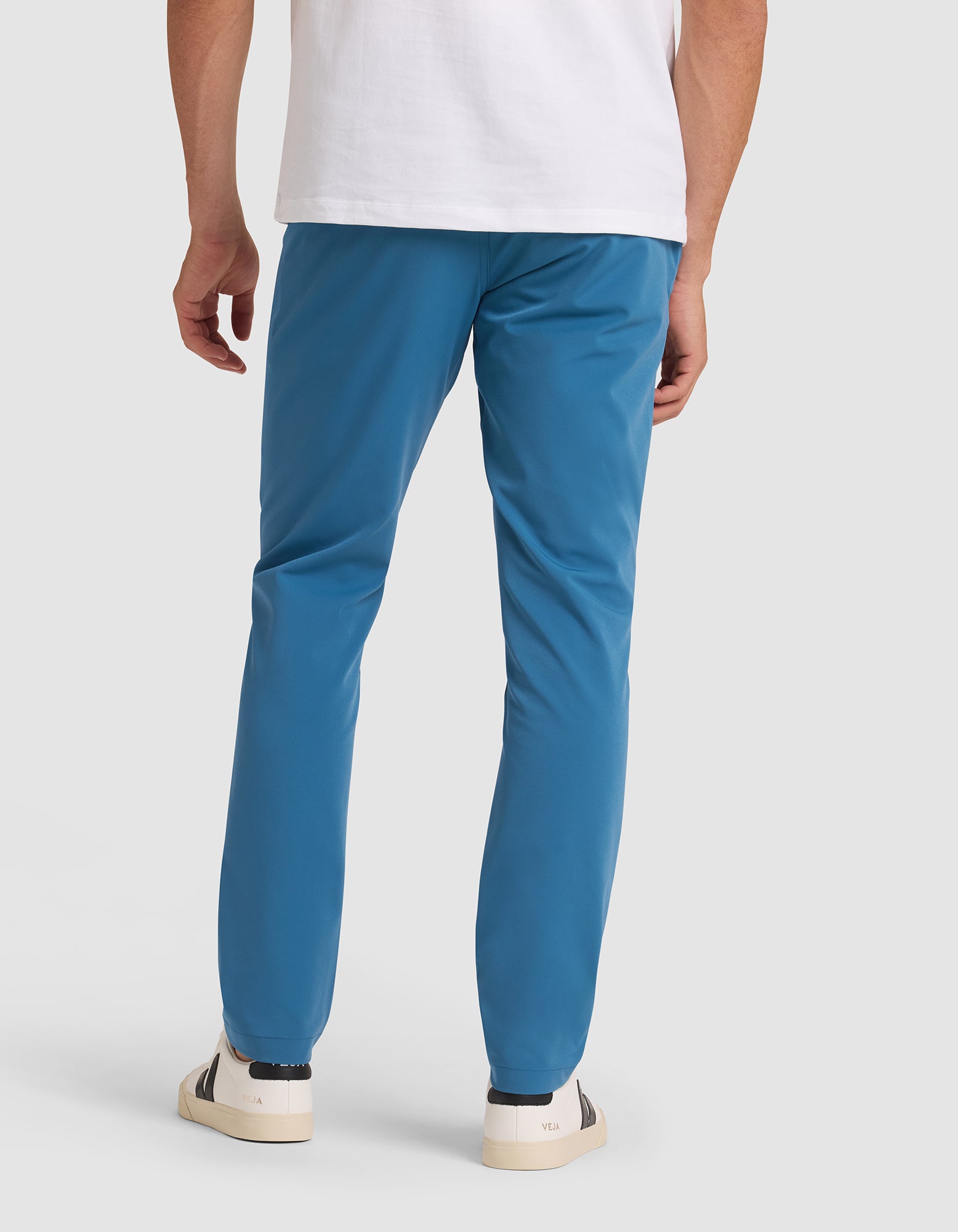 A person models the back view of the Cozy Earth Men's Everywhere Pant, paired with a white t-shirt and white sneakers with dark accents, against a plain light background.  |Color:Wave