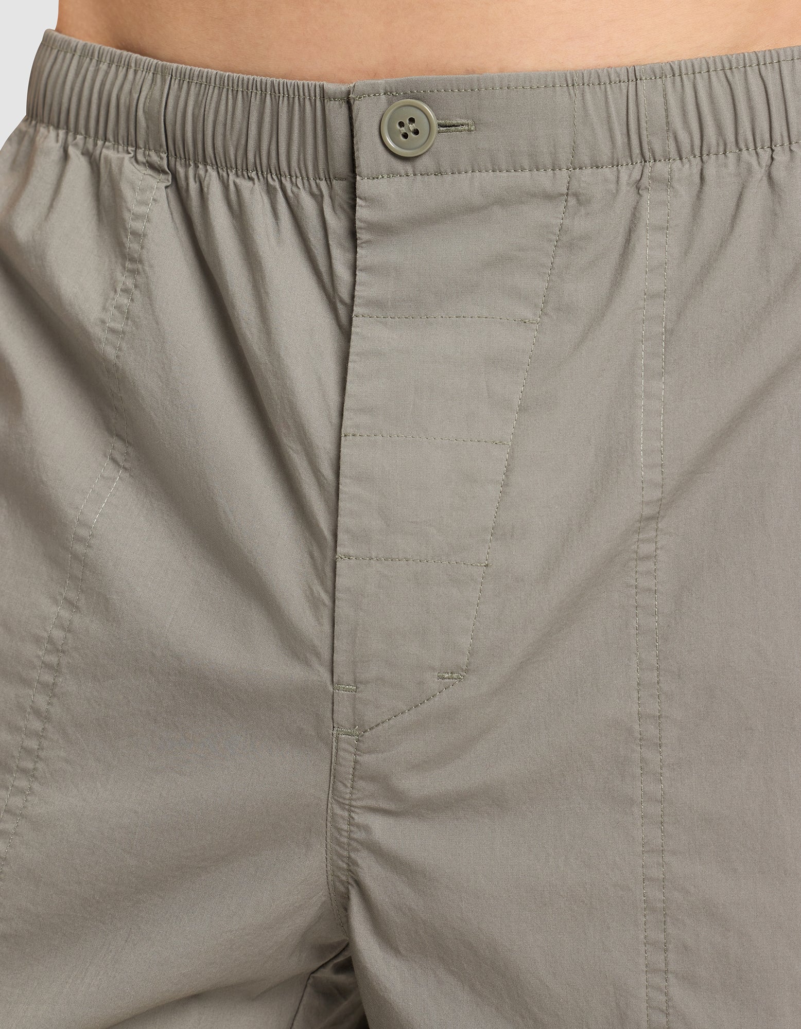 Close-up of a person wearing Cozy Earth Men's Sleep Pant in light gray, featuring an elastic waist, button closure, and visible stitching on lightweight, subtly textured fabric. 