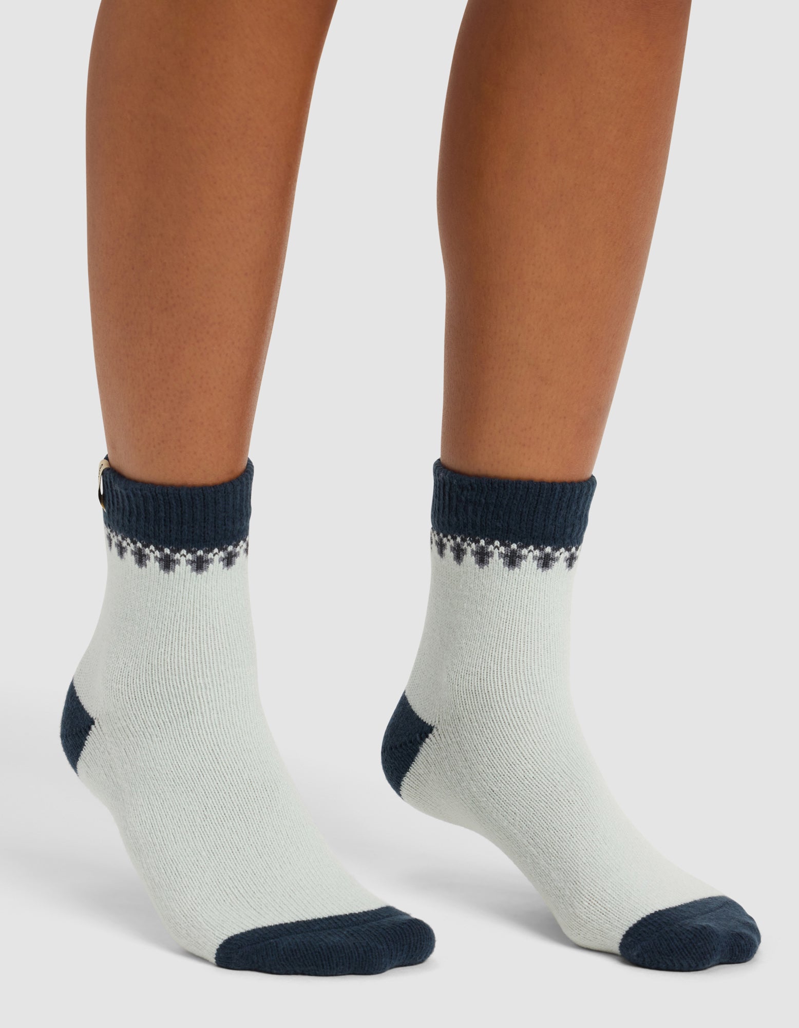 A person wearing Cozy Earth's The Mistletoe Plush Modern Crew Sock stands on a white background.
