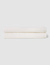 Two neatly folded Cozy Earth Nantucket Bath Sheets are stacked atop each other against a plain, light-colored background.|Color:White