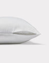 The Cozy Earth Pillow Protector is displayed lying on its side, featuring a subtle checkered pattern and a partially open zipper that reveals the inner filling. The background is plain white.