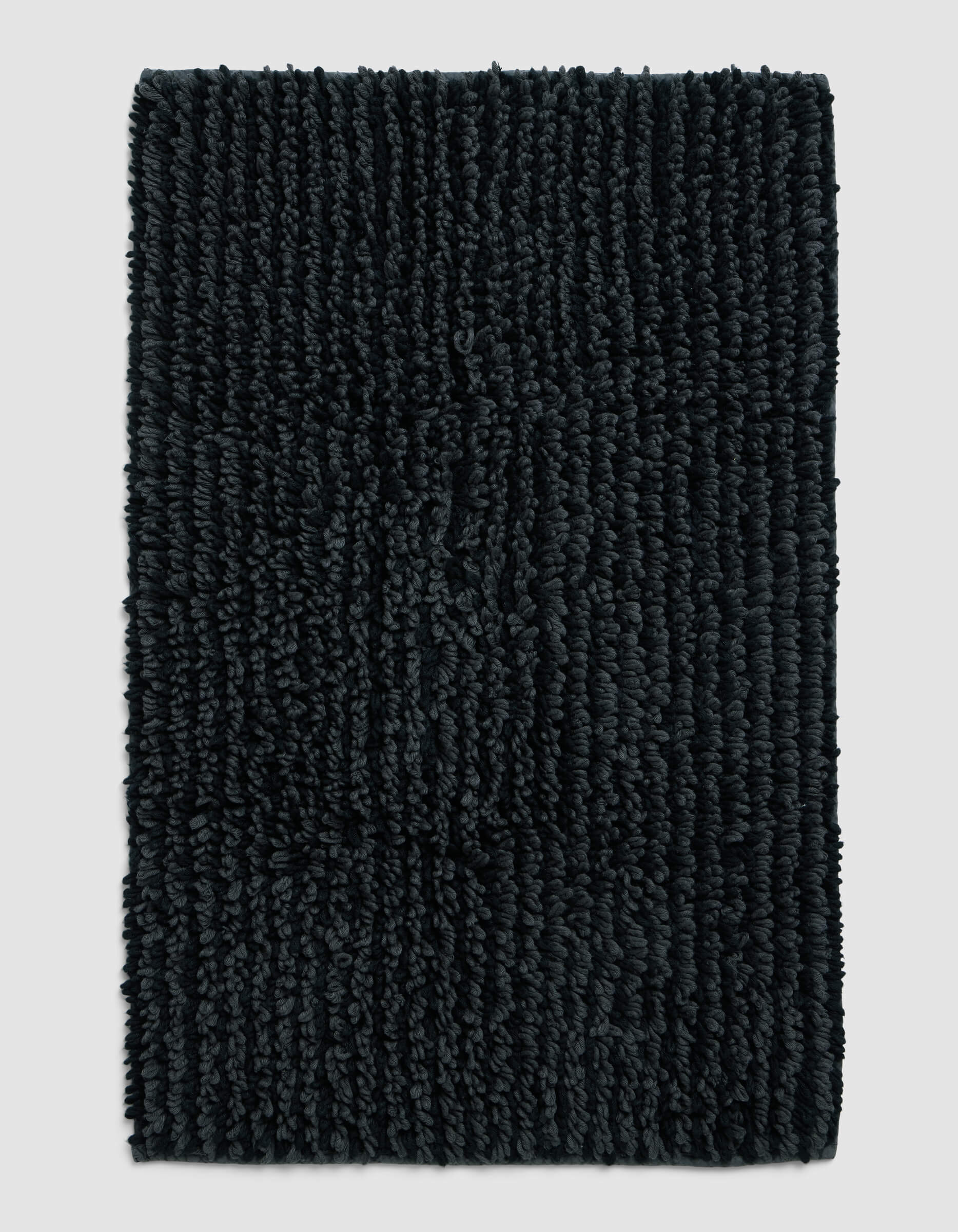 The Cozy Earth Plush Loop Bath Mat, rectangular and dark gray with thick textured fibers, is displayed on a plain light gray background.|Color:Graphite