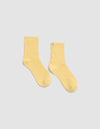 The Plush Lounge Quarter Socks by Cozy Earth in light yellow, featuring a ribbed crew design, is displayed laid flat on a light gray background.|Color:Daisy