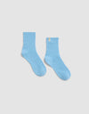 The Plush Lounge Quarter Sock by Cozy Earth in light blue features a ribbed design and a small yellow tag on the upper edge, shown against a plain white background.|Color:Harbor