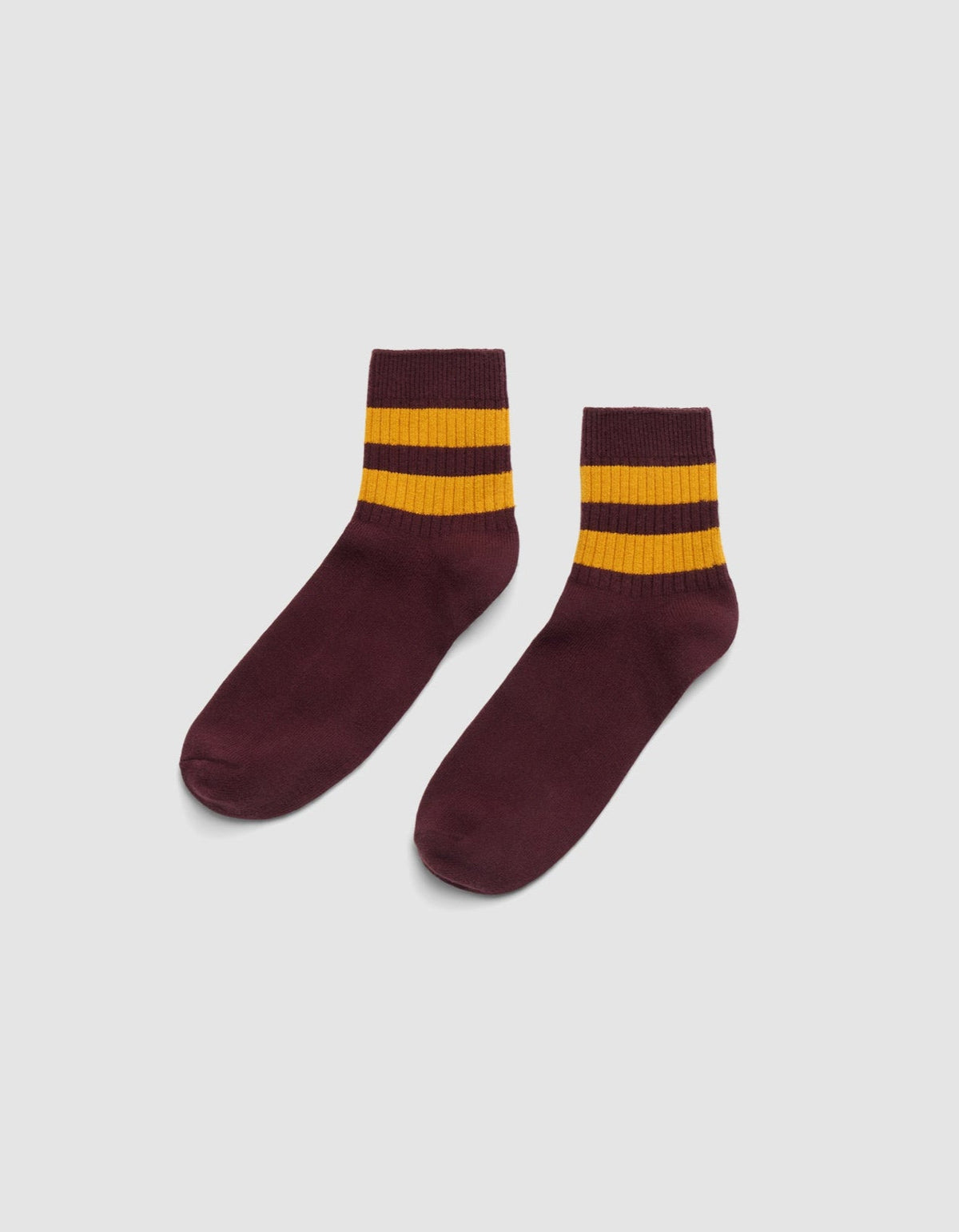 The Women's Sadie Sock by Cozy Earth is shown in maroon with two thick yellow stripes near the top, set against a plain white background. |Color:Burgundy/Goldenrod