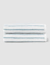 Two Striped Luxe Hand Towels by Cozy Earth, featuring thin teal horizontal stripes on white, are neatly folded and stacked against a light gray background. |Color:Brook Stripe