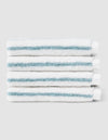 Five Striped Luxe Washcloths by Cozy Earth, white with light blue stripes, are neatly stacked against a plain light gray background. |Color:Brook Stripe