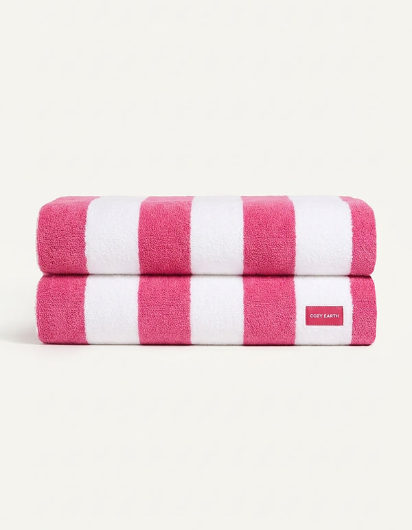 Two neatly folded towels from the Seaside Resort Towel Bundle by Cozy Earth, featuring wide pink and white stripes, are stacked together. A small white tag with red "COZY EARTH" text is visible on the bottom towel.|Color:Punch Stripe