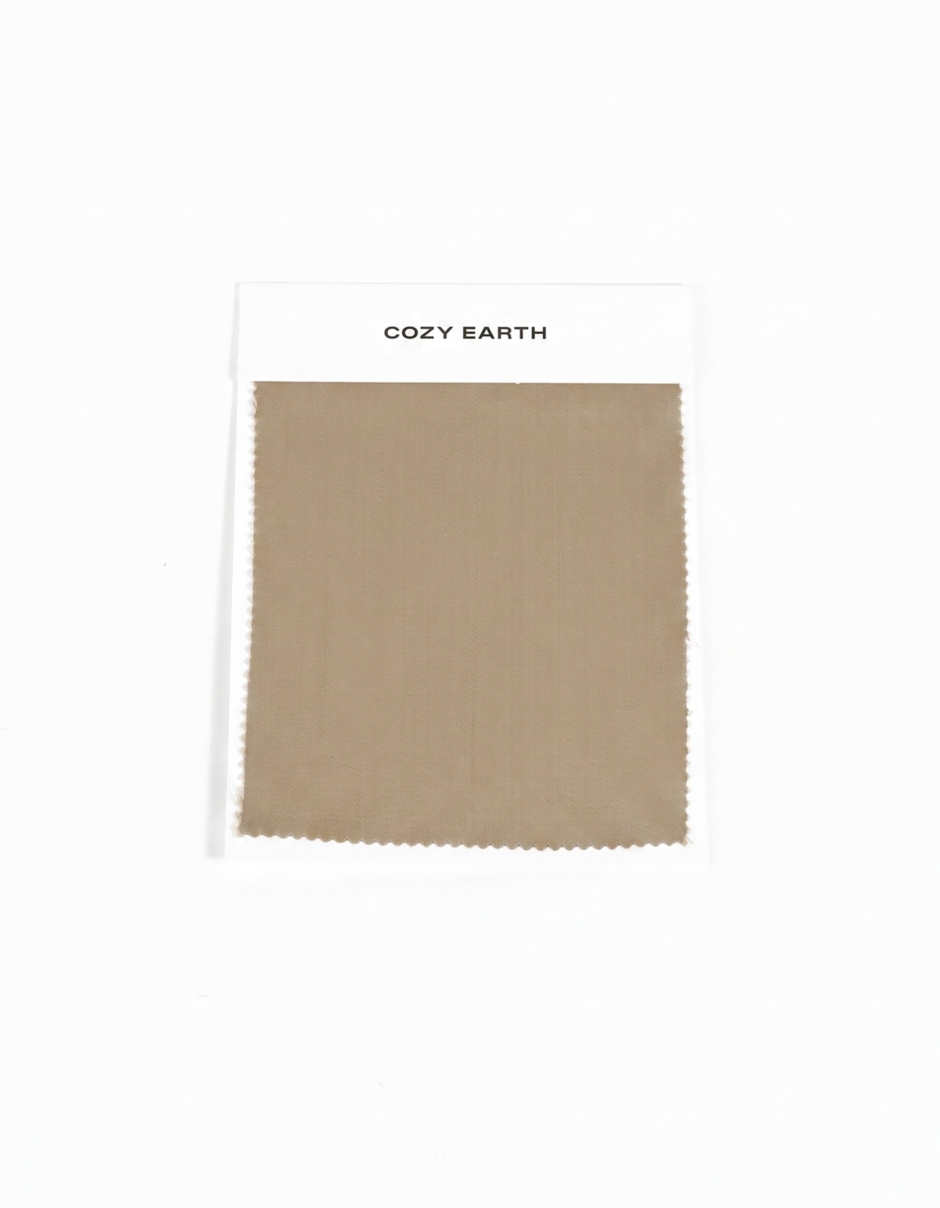 A rectangular beige swatch of Soft-Wash Cotton Sheet from Cozy Earth is attached to a white card labeled "Cozy Earth" on a plain white background.