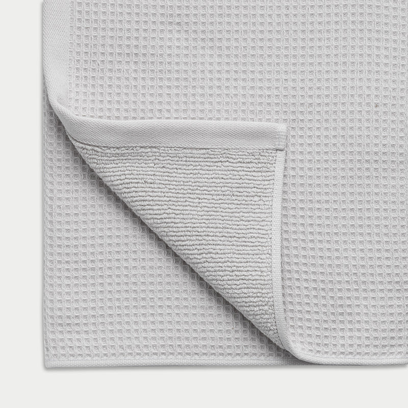 Waffle Bath Towel in the color Light Grey. Photo of Light Grey Waffle Bath Towel taken close up showing the corner of the towel