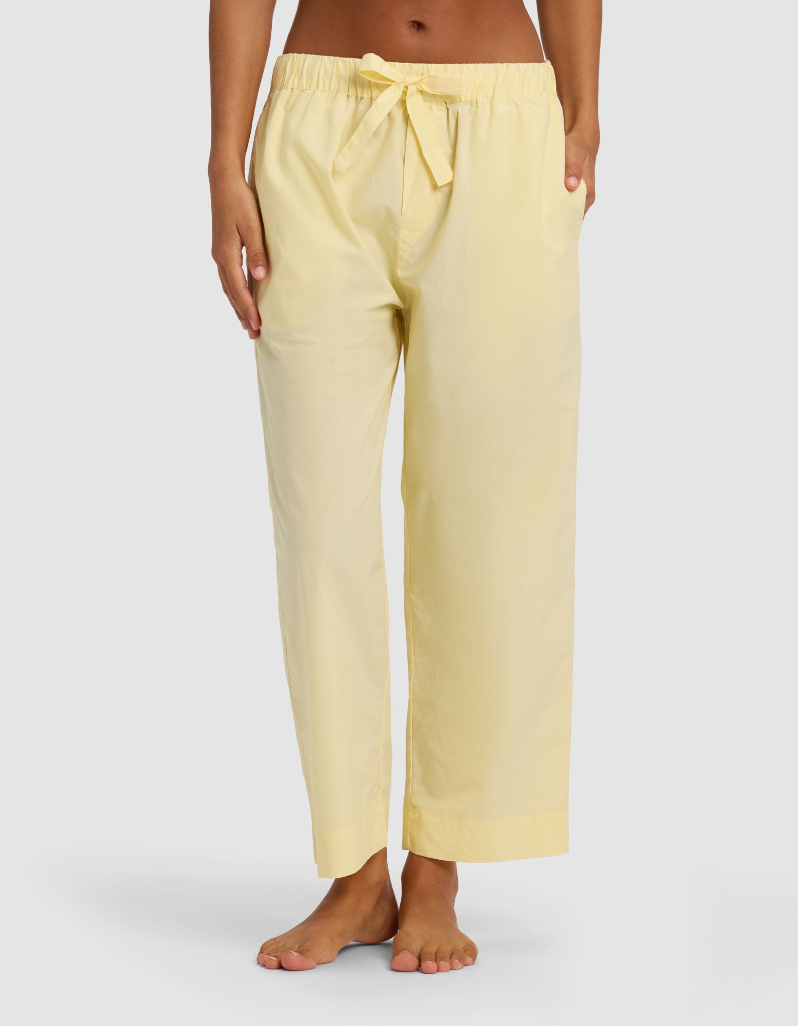A person stands barefoot against a plain background wearing Cozy Earth Women's Sutton Cropped Pajama Pant in light yellow, featuring a loose fit, drawstring waist, and side pockets.|Color:Meringue