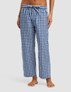 A woman models the Cozy Earth Women's Sutton Cropped Pajama Pant, featuring a blue and white checkered pattern and drawstring waist. Only her bare feet and lower half are visible against a plain background.|Color:Pacific Gingham