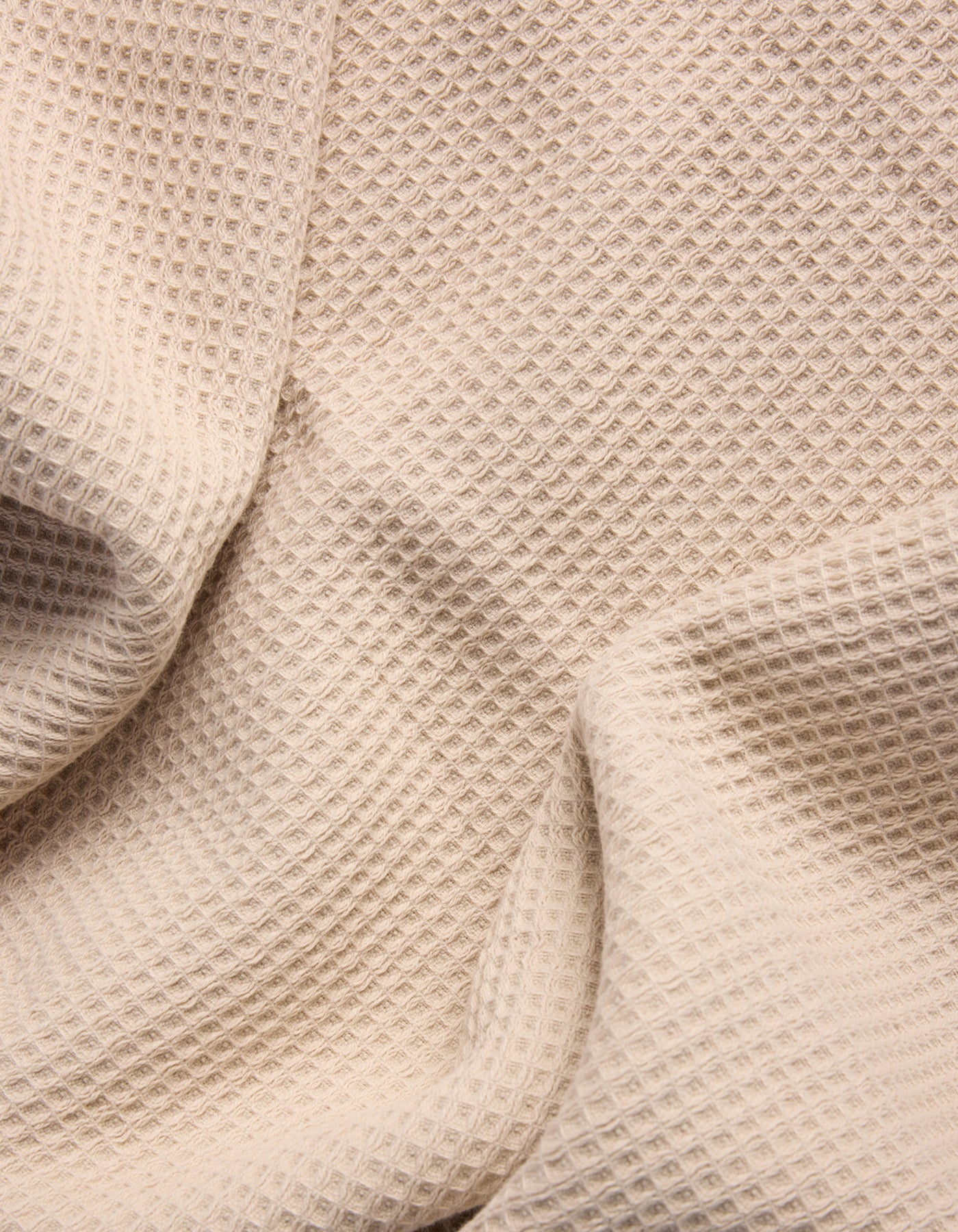 A close-up of Cozy Earth's Waffle Bath Sheets in beige, showing their textured, waffle-like pattern with gentle folds and shadows. |Color:Birch