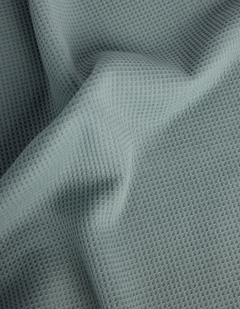 The Cozy Earth Waffle Bath Towel Set features light gray, waffle-textured fabric with a soft, grid-like pattern and gentle folds across the surface.