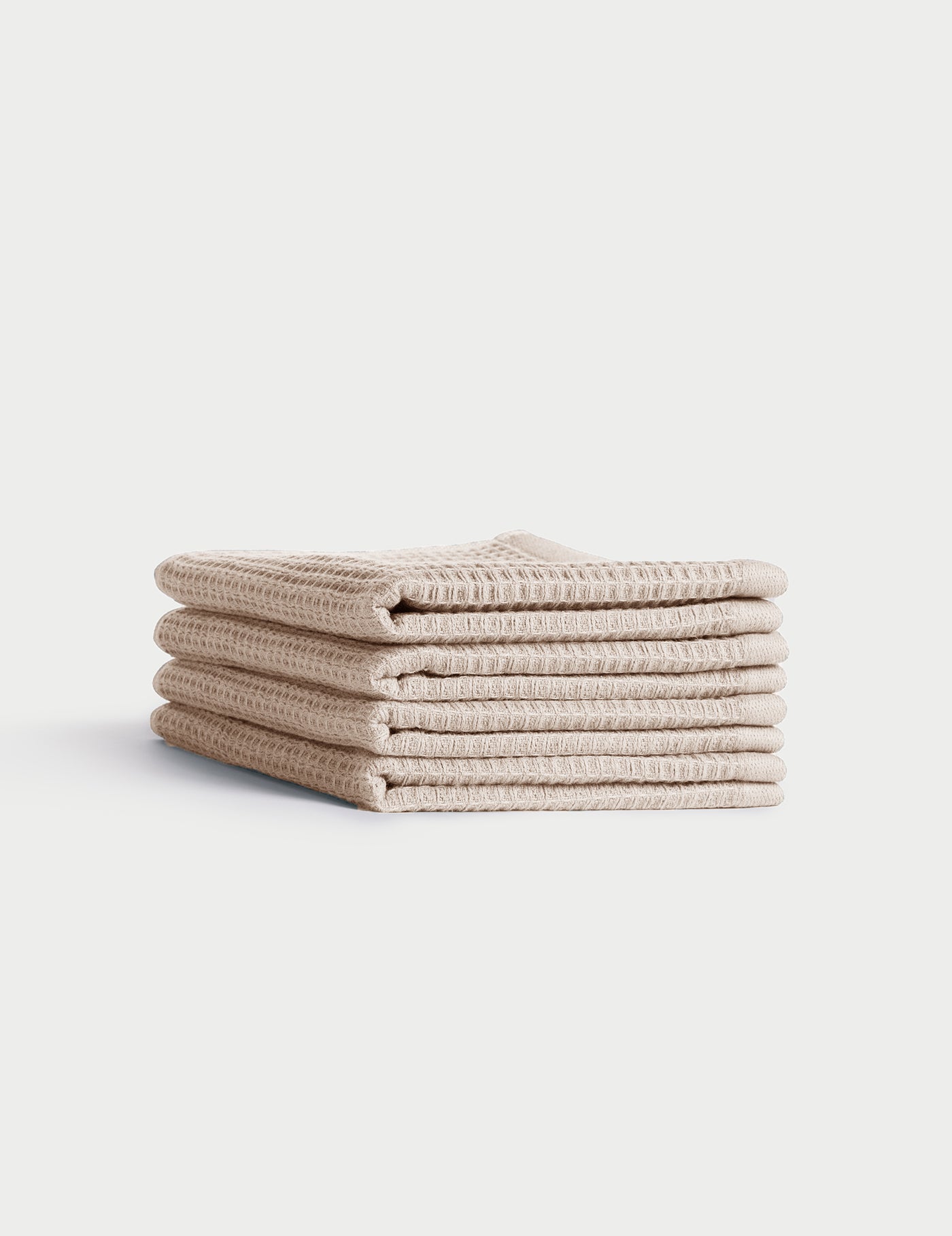 A stack of four neatly folded beige Waffle Washcloths by Cozy Earth, featuring a textured waffle-weave, displayed on a plain white background. |Color:Birch