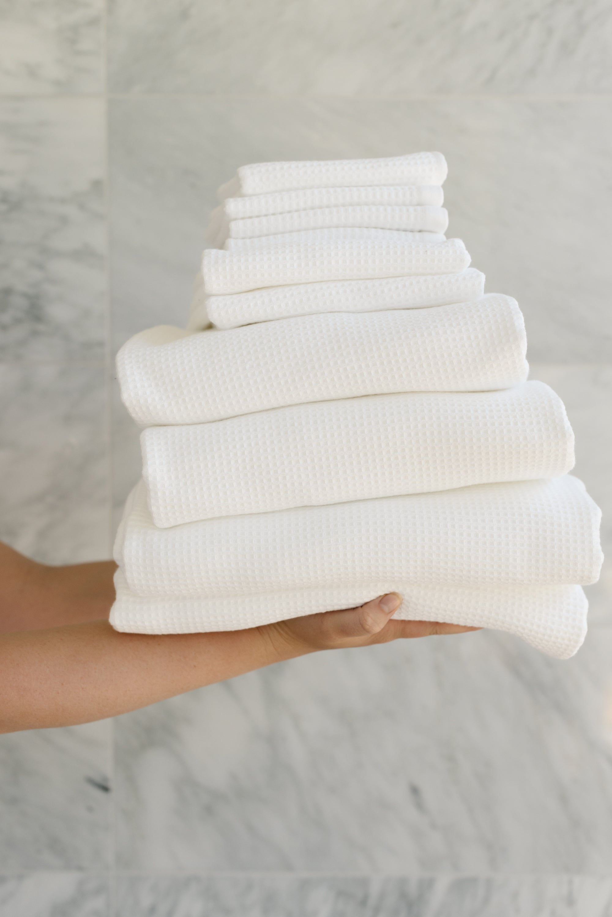 Complete Waffle Bath Bundle in the color White. Photo of White Complete Waffle Bath Bundle taken while being held by a persons outreached hands 