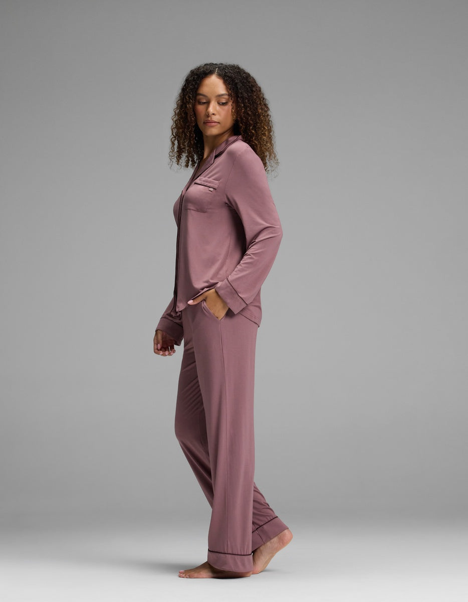 A person wearing a dusty mauve Women’s Bamboo Stretch-Knit Long Sleeve Pajama Set, featuring a button-down shirt and matching trousers.