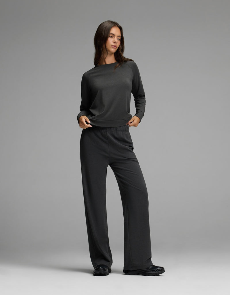 A woman stands in a relaxed pose against a plain gray background, wearing the Cozy Earth Women’s Brushed Bamboo Wide Leg Pull On Pant & Pullover Crew Set in charcoal.
