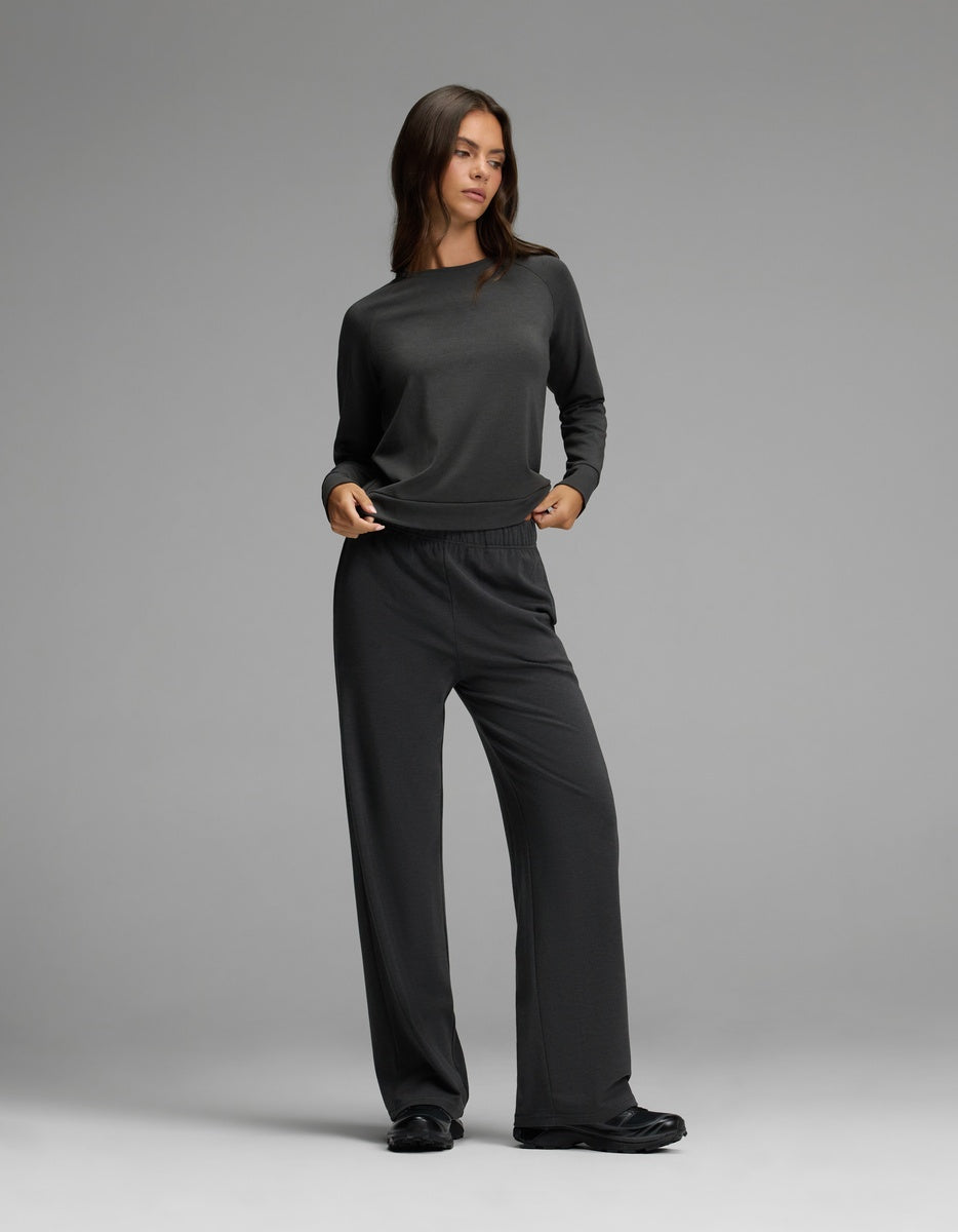A woman stands in a relaxed pose against a plain gray background, wearing the Cozy Earth Women’s Brushed Bamboo Wide Leg Pull On Pant & Pullover Crew Set in charcoal.|Color:Charcoal