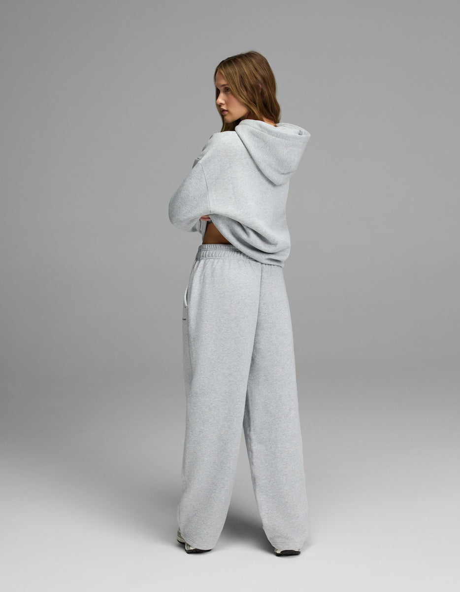 A person stands with their back turned, wearing the Cozy Earth Women’s CityScape Hoodie & Wide Leg Pant Set in light gray against a plain gray background.