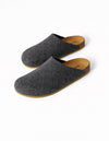 The Lakehouse Clog by Cozy Earth features a minimalist design with dark grey woolen uppers and natural brown soles. It has a closed toe, open back, and is ideal for indoor wear. A logo is visible on the insole, all showcased on a white background. |Color:Graphite