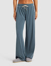 A person wears Cozy Earth's Women's Studio Wide Leg Pant in blue-gray, paired with gray slippers, standing against a plain light background. Only the lower half of the body is shown.|Color:Dawn