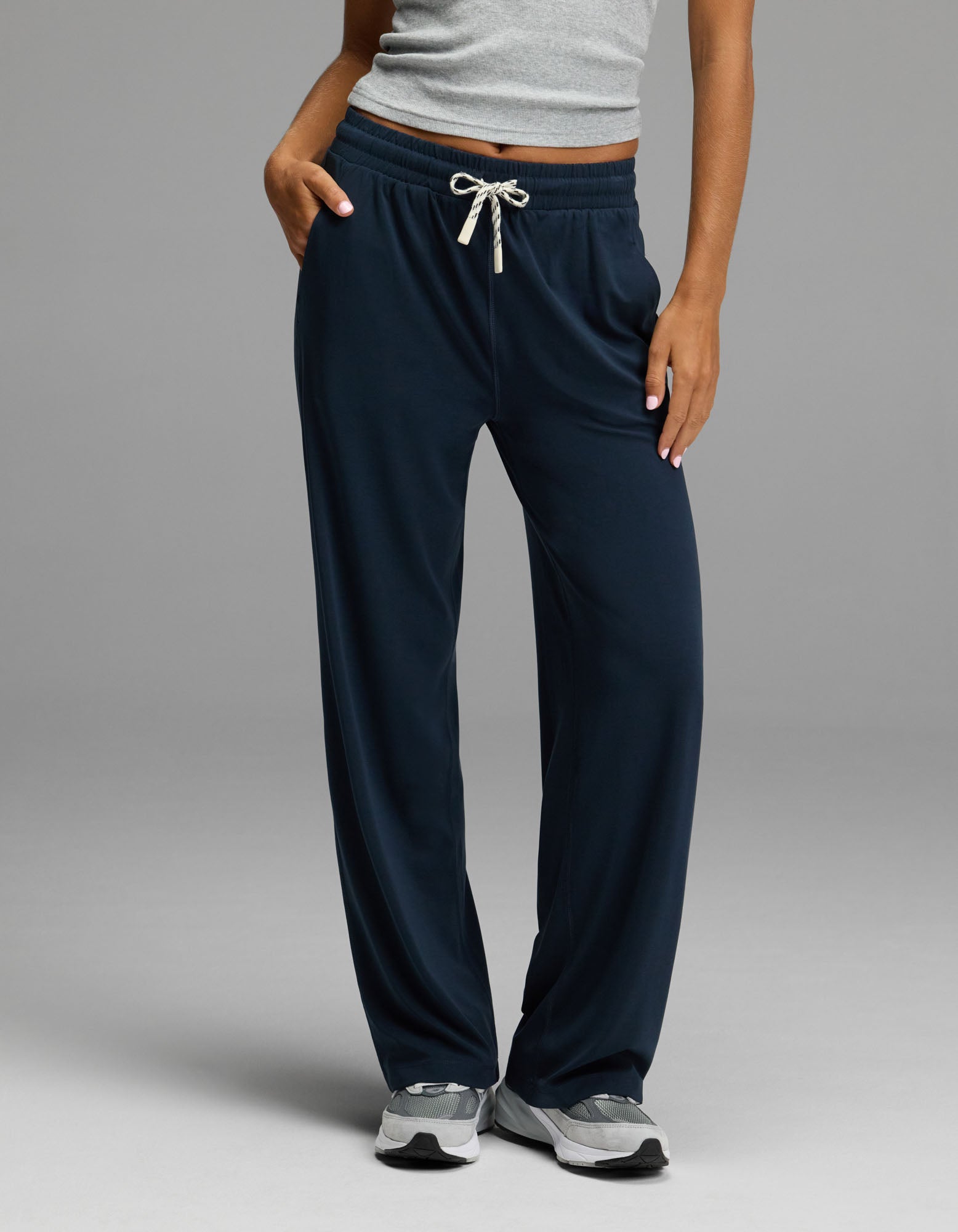 A person wearing Cozy Earth’s Women’s Studio Wide Leg Pant in Eclipse stands with one hand in their pocket against a plain background.