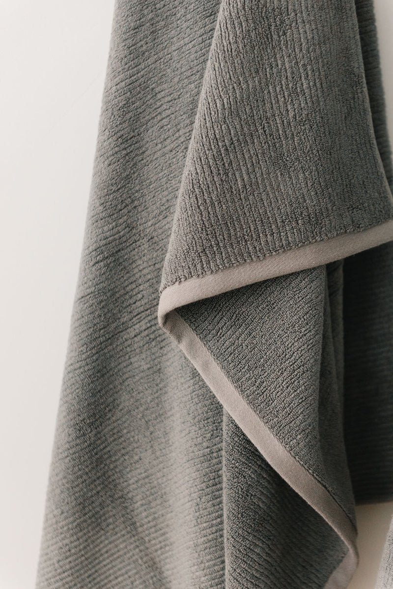 Ribbed Terry Hand Towel in the color Charcoal. Photo of Ribbed Terry Hand Towel taken with the Ribbed Terry Hand Towel resting on a bathroom sink.