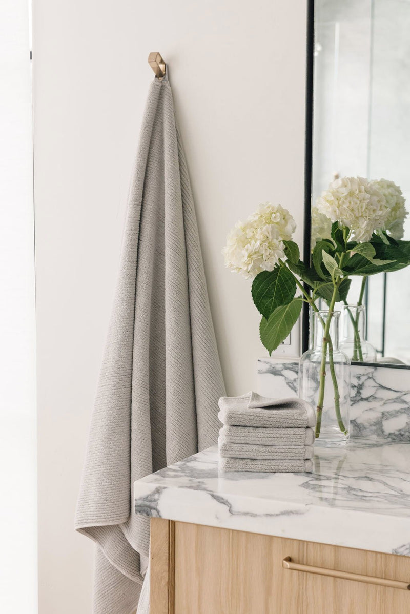 Ribbed Terry Bath Sheets in the color Light Grey. Photo of product taken in a bathroom next to a sink.