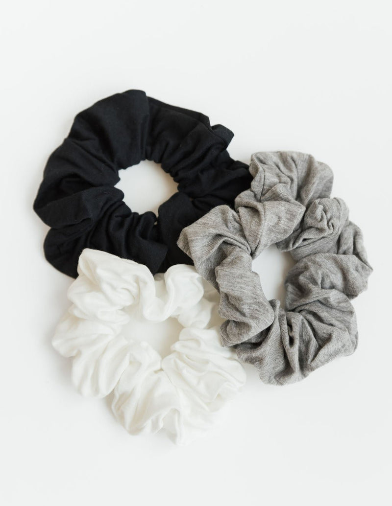 A group of three stretch knit scrunchies in Black, Ivory, and Grey