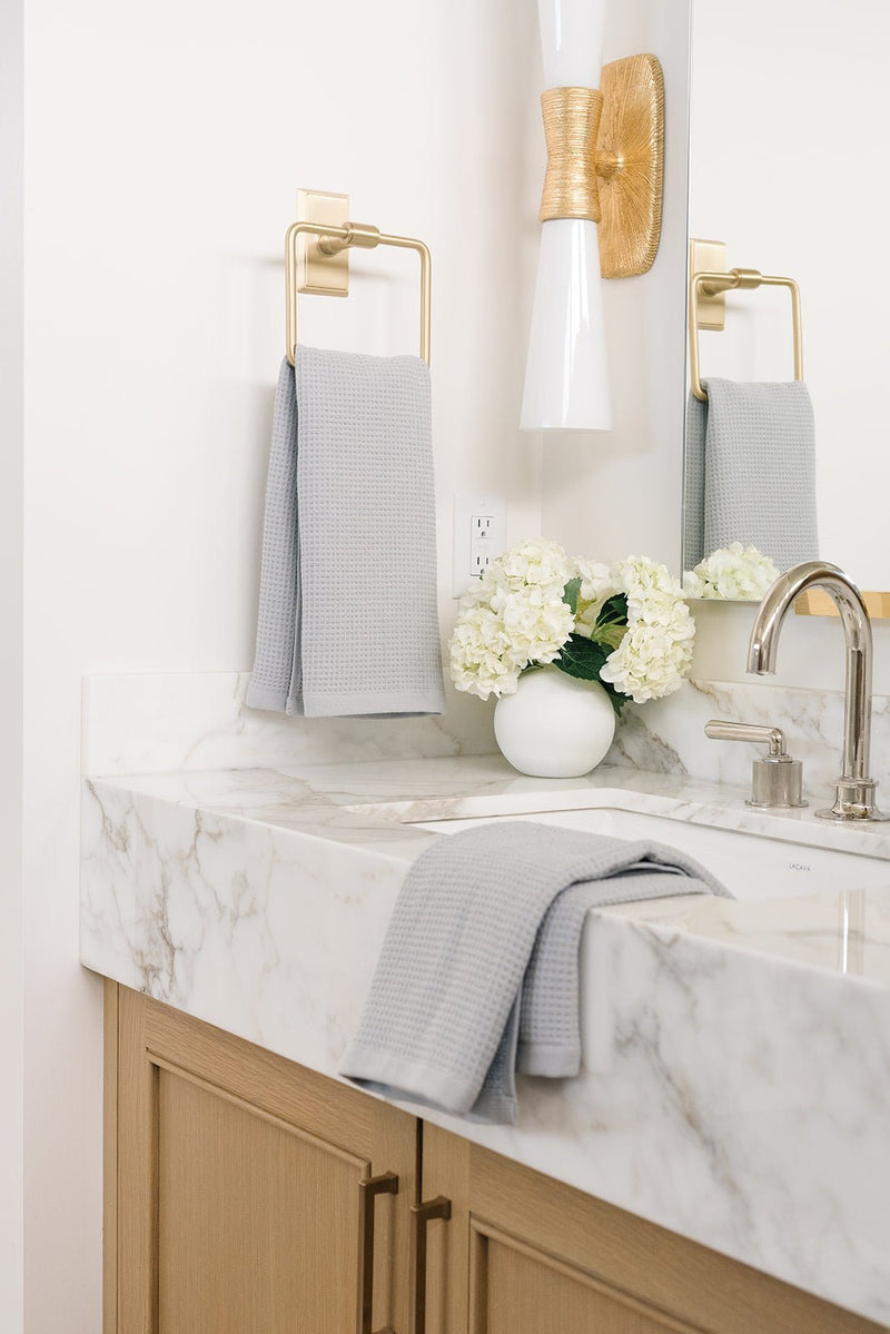 Waffle Hand Towel in the color Harbor Mist. Photo of Harbor Mist Waffle Hand Towel taken with one of the Waffle Hand Towels in Harbor Mist hung from a towel ring. The other Waffle Hand Towel Harbor Mist is resting on a bathroom sink.