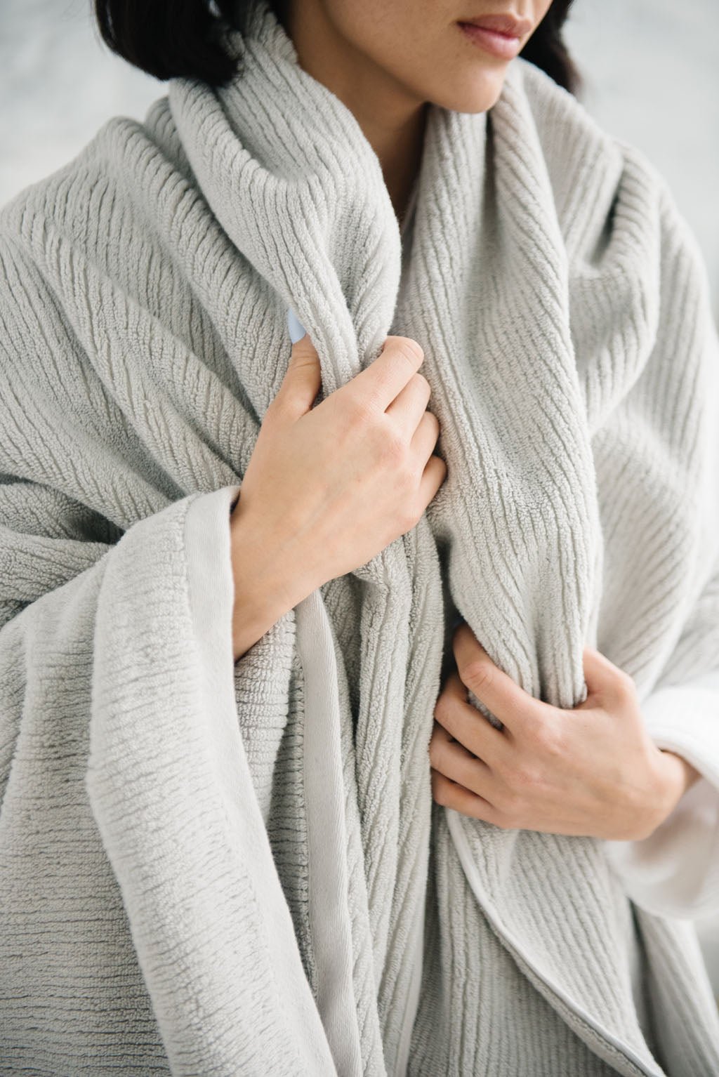 Ribbed Terry Bath Sheets in the color Light Grey. Photo of product taken in a bathroom as a woman wears the towel. |Color:Light Grey