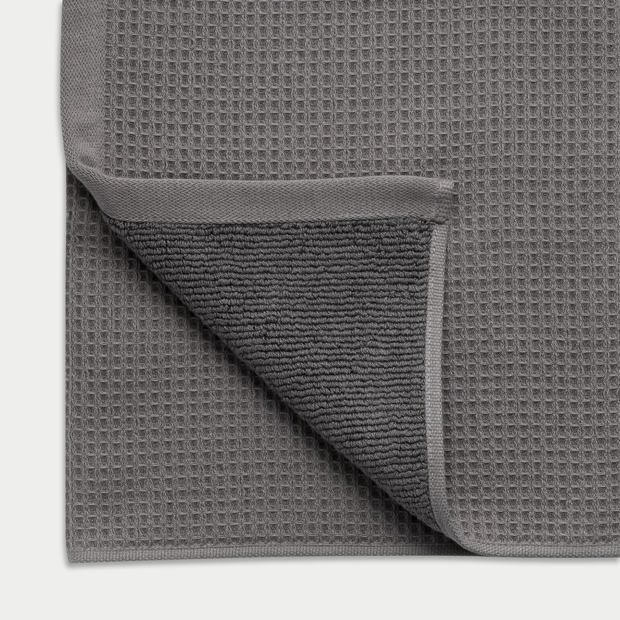 Waffle Bath Towel in the color Charcoal. Photo of White Waffle Bath Towel taken as a close up of the Waffle Bath Towel. The picture shows the corner of the towel and a white background |Color: Charcoal