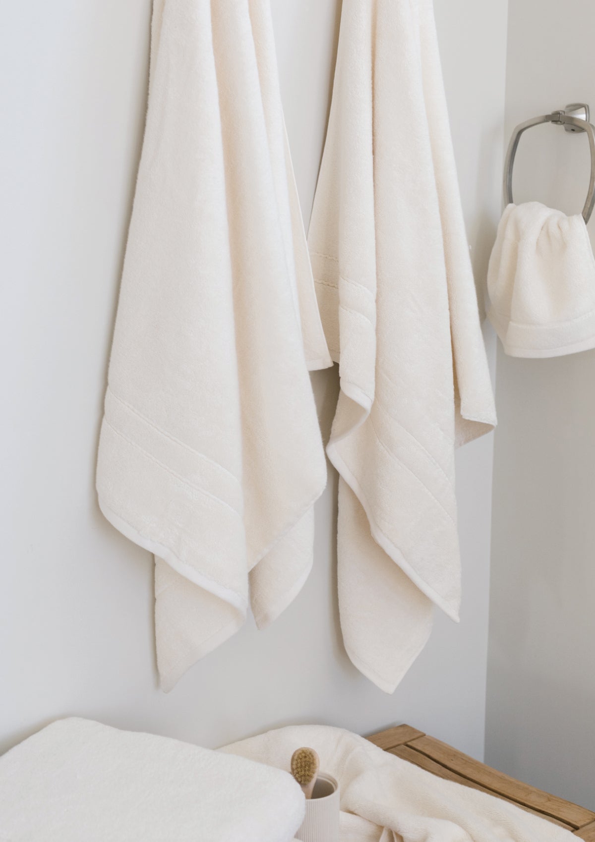 Premium Plush Bath Towels in the color Creme. Photo of Premium Plush Bath Towels taken in a bathroom showing the towels which are hung from a towel rack. 